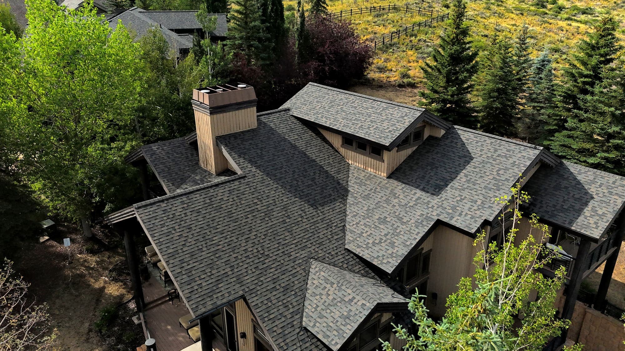 A mountain home's existing weathered asphalt shingle roof, photographed from above.
